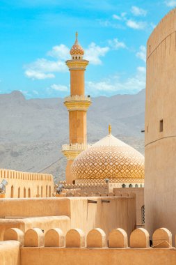 Al Qala 'a Camii, kubbe ve minareyle süslenmiş. Önünde Nizwa kalesi duvarları, Nizwa, Umman sultanı.