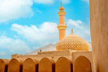 Al Qala 'a Camii, kubbe ve minareyle süslenmiş. Önünde Nizwa kalesi duvarları, Nizwa, Umman sultanı.