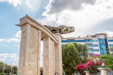 Old war memorial with soviet jet fighter and modern buildings in the  downtown streets of Hargeisa, Somaliland, Somalia clipart