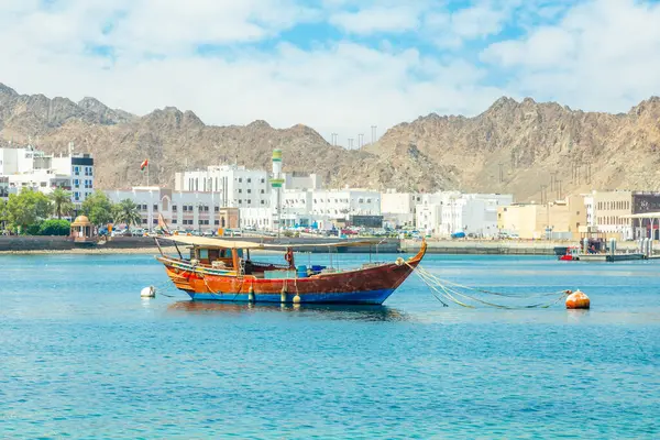 Mutrah gezinti güvertesi dağ sıraları ve deniz körfezi ile geleneksel dhow teknesi, Muscat, Sultan Umman