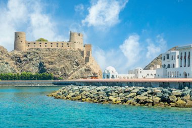 Kayaların üzerinde duran Arap Al Jalali şatosuna ve beyaz saray binalarına bakın, Muscat, Umman