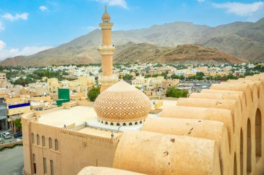 Al Qala 'a Camii Kubbe ve minareyi süsleyip Nizwa şehir sokaklarını ve kale duvarlarını ön planda, Nizwa, Umman sultanı