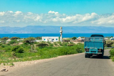 Tadjourah körfezi boyunca uzanan yol. Arkasında köy, cami ve dağlar, Tajourah, Cibuti.