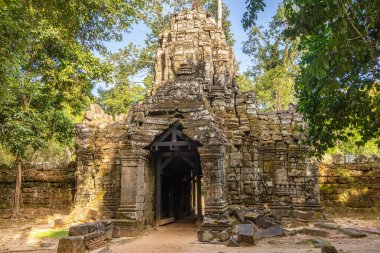 Ancient hindu Ta Som khmer  ruined temple entance gopura gate with stone face on top and statues, Angkor Archaeological Park, Siem Reap, Cambodia clipart