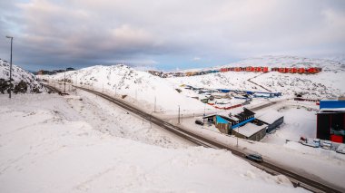 Road between snow hills and Inuit houses in the background, Nuuk city, Greenland clipart