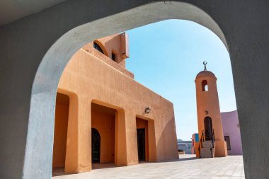 Nefes kesici bir manzara eşsiz mimari tasarımlar sergiliyor, açık mavi gökyüzünün altında güzel bir şekilde sıcak renklerle çerçevelenmiş.