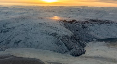 Greenlandic ice cap with frozen mountains and fjords aerial view during the sunset time, near Kangerlussuaq, Greenland clipart