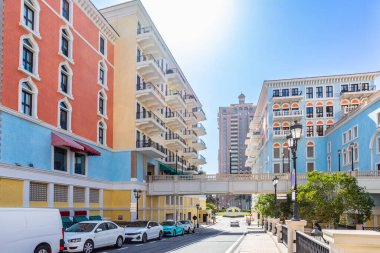 Qanat Quartier Venedik lüks yerleşim bölgesinin otantik renkli binaları ve ön planda arabaları olan yolu, Pearl Island, Doha, Katar