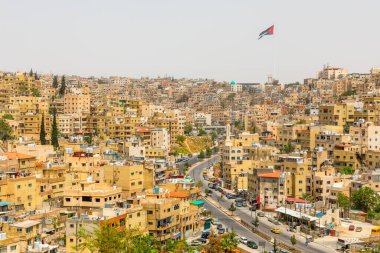 Amman şehrinin şehir merkezindeki tepelere yoğun bir şekilde dağılmış pek çok mesken evi rüzgarda dalgalanan ulusal bayrak, Ürdün Krallığı