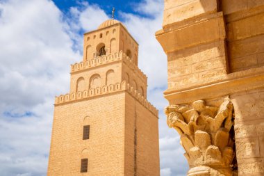 Eski sütun ve manzara Uqba Büyük Camii 'nin minare kulesini gösteriyor mavi gökyüzünde bulutlar, Kairouan, Tunus