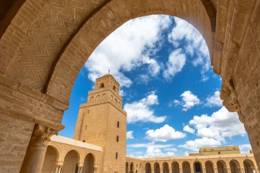 Mavi gökyüzünde bulutlar olan Uqba Büyük Camii 'nin minare kulesine kemer görüntüsü, Kairouan