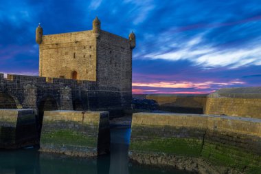 Essaouira Sqala Limanı, Portekiz şatosu. Günbatımı ışıklarında taş duvar ve hendek ön planda, Essaouira, Fas