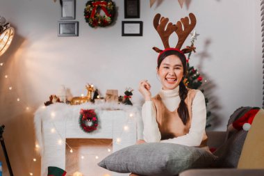 Bir grup mutlu Asyalı arkadaş Noel 'i kutluyor ve Noel ağacını içeride süslüyor. Noel hediyeli güzel kadın. Yeni yıl partisi. Kadın elleri Noel ağacını süslüyor Kırmızı top, takı gibi.