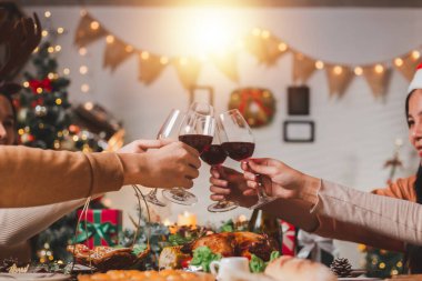 Bir grup genç Asyalı arkadaş Noel arifesini kutlamak için şarap kadehlerine tezahürat yapıyor. Asyalı Dostlar Partisi. İçkinin ve kutlamanın tadını çıkarıyorlar. Mutlulukla kadeh tokuşturalım..