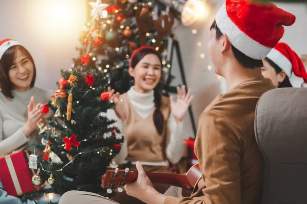아시아 청년들이 크리스마스 이브를 축하하는 거실에서 우쿨렐레를 연주하며 즐거운 시간을 — 스톡 사진