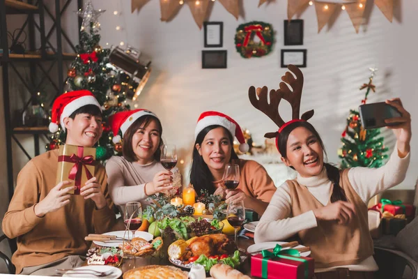 stock image Group of young adult Asian Friends holiday party dinner at home around the table taking selfie photo. Celebrate Christmas. People having dinner together talk and laugh with joy in Christmas eve night.