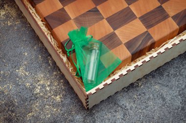 End cutting board on a dark textured background. Kitchen utensils made of natural wood. Expensive vintage items. Luxurious quality woodworking. Chess pattern on a wooden board