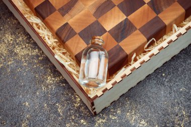 End cutting board on a dark textured background. Kitchen utensils made of natural wood. Expensive vintage items. Luxurious quality woodworking. Chess pattern on a wooden board