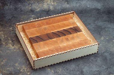 End cutting board on a dark textured background. Kitchen utensils made of natural wood. Expensive vintage items. Luxurious quality woodworking. Chess pattern on a wooden board