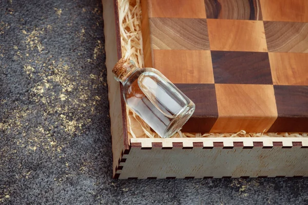 End cutting board on a dark textured background. Kitchen utensils made of natural wood. Expensive vintage items. Luxurious quality woodworking. Chess pattern on a wooden board