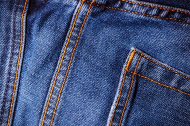 Kot pantolon giyiyordu. Makine dikişi yakın. Mavili Denim dokusu. Eski giysileri tamir etme kavramı. Dikiş fabrikası. Modaya uygun yaşlanma kıyafetleri..