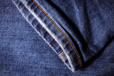 Kot pantolon giyiyordu. Makine dikişi yakın. Mavili Denim dokusu. Eski giysileri tamir etme kavramı. Dikiş fabrikası. Modaya uygun yaşlanma kıyafetleri..