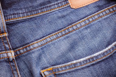 Deri etiketli kot pantolon giymiş. Makine dikişi yakın. Mavili Denim dokusu. Eski giysileri tamir etme kavramı. Dikiş fabrikası. Modaya uygun yaşlanma kıyafetleri..