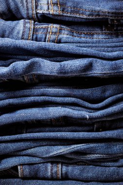 Kot pantolon giyiyordu. Makine dikişi yakın. Mavili Denim dokusu. Eski giysileri tamir etme kavramı. Dikiş fabrikası. Modaya uygun yaşlanma kıyafetleri. Kot yığını. 