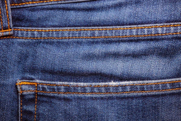 Worn denim trousers. Machine stitch close up. Denim texture in blue. The concept of repairing old clothes. Sewing factory. Fashionable aging clothes.