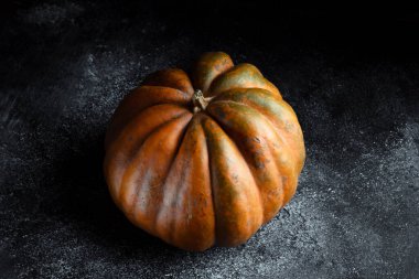 Koyu arkaplanda taze balkabağı. Dokulu turuncu balkabağı. Sonbahar hasadı. Balkabağı turtası için içerik.