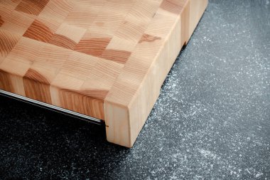 Koyu dokulu arka planda kesme tahtası. Doğranmış sebzeler, et ve diğer ürünler için paslanmaz tepsi. Lüks kaliteli ahşap işçiliği. Tahtada satranç deseni.