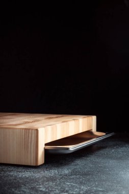 Koyu dokulu arka planda kesme tahtası. Doğranmış sebzeler, et ve diğer ürünler için paslanmaz tepsi. Lüks kaliteli ahşap işçiliği. Tahtada satranç deseni.