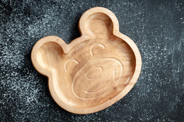A plate for children in the shape of a bear is made of wood for serving snacks, fruits, nuts, cheeses, meat and original serving of main dishes. Accessories for a modern kitchen.