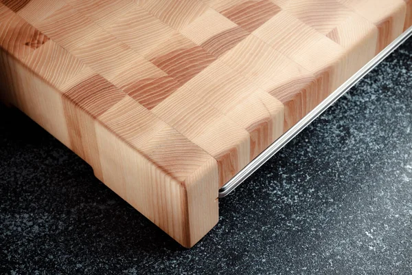 End cutting board on a dark textured background. Stainless tray for chopped vegetables, meat and other products. Luxurious quality woodworking. Chess pattern on a wooden board.