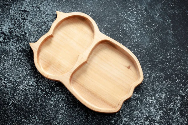 A children\'s plate in the shape of an owl is made of wood for serving snacks, fruits, nuts, cheeses, meat and original serving of main dishes. Accessories for a modern kitchen.