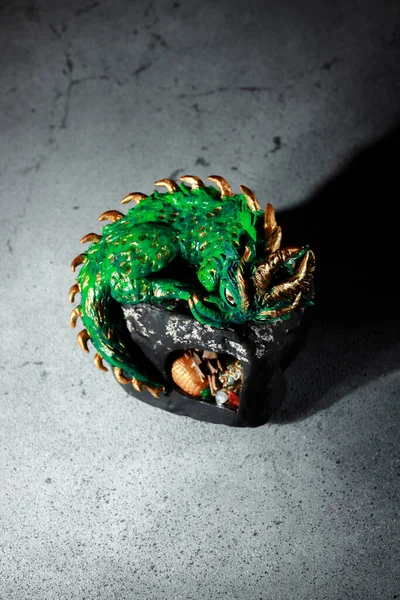 A green dragon with golden spikes sitting on a large stone. Figurine of the symbol of 2024. Dark background with space for an inscription. Invitation card for Chinese New Year.