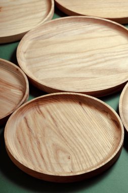 Yeşil arka planda tahta düz plakalar. Modern mutfak ürünleri. Ekolojik sofra takımı kavramı. Sıfır emisyon.