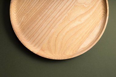 Koyu yeşil arka planda tahta düz plakalar. Ekolojik sofra takımı kavramı. Modern mutfak ürünleri. Doğal uyum: Çevre dostu bir mutfakta ahşap tabaklar. Sıcak lamba gölgeleri.