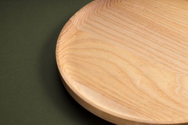 Koyu yeşil arka planda tahta düz plakalar. Ekolojik sofra takımı kavramı. Modern mutfak ürünleri. Doğal uyum: Çevre dostu bir mutfakta ahşap tabaklar. Sıcak lamba gölgeleri.