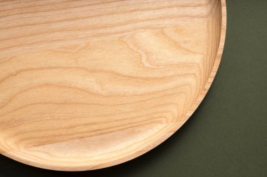 Koyu yeşil arka planda tahta düz plakalar. Ekolojik sofra takımı kavramı. Modern mutfak ürünleri. Doğal uyum: Çevre dostu bir mutfakta ahşap tabaklar. Sıcak lamba gölgeleri.