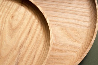 Koyu yeşil arka planda tahta düz plakalar. Ekolojik sofra takımı kavramı. Modern mutfak ürünleri. Doğal uyum: Çevre dostu bir mutfakta ahşap tabaklar. Sıcak lamba gölgeleri.