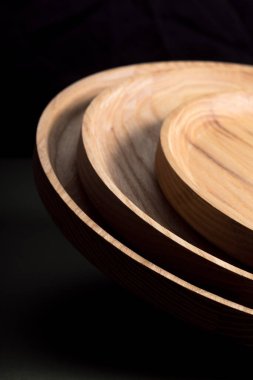 Koyu yeşil arka planda tahta düz plakalar. Ekolojik sofra takımı kavramı. Modern mutfak ürünleri. Doğal uyum: Çevre dostu bir mutfakta ahşap tabaklar. Sıcak lamba gölgeleri.