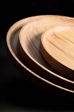 Koyu yeşil arka planda tahta düz plakalar. Ekolojik sofra takımı kavramı. Modern mutfak ürünleri. Doğal uyum: Çevre dostu bir mutfakta ahşap tabaklar. Sıcak lamba gölgeleri.