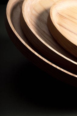 Koyu yeşil arka planda tahta düz plakalar. Ekolojik sofra takımı kavramı. Modern mutfak ürünleri. Doğal uyum: Çevre dostu bir mutfakta ahşap tabaklar. Sıcak lamba gölgeleri.