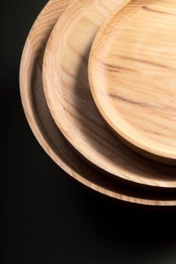 Koyu yeşil arka planda tahta düz plakalar. Ekolojik sofra takımı kavramı. Modern mutfak ürünleri. Doğal uyum: Çevre dostu bir mutfakta ahşap tabaklar. Sıcak lamba gölgeleri.