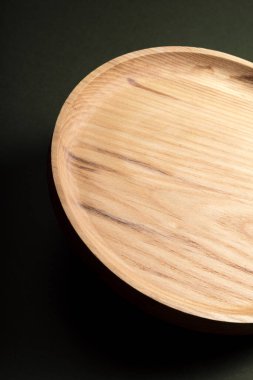 Koyu yeşil arka planda tahta düz plakalar. Ekolojik sofra takımı kavramı. Modern mutfak ürünleri. Doğal uyum: Çevre dostu bir mutfakta ahşap tabaklar. Sıcak lamba gölgeleri.