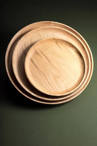Flache Holzteller Auf Dunkelgrünem Hintergrund Das Konzept Des Ökologischen Geschirrs lizenzfreie Stockfotos