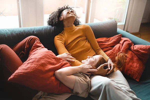 年轻的多种族年轻女性躺在沙发上拥抱 同性人亲密和亲密关系 多元人融合的概念 — 图库照片