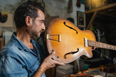 A luthier checks an hollow body guitar neck in his workshop to verify alignment - people, arts and craft concept