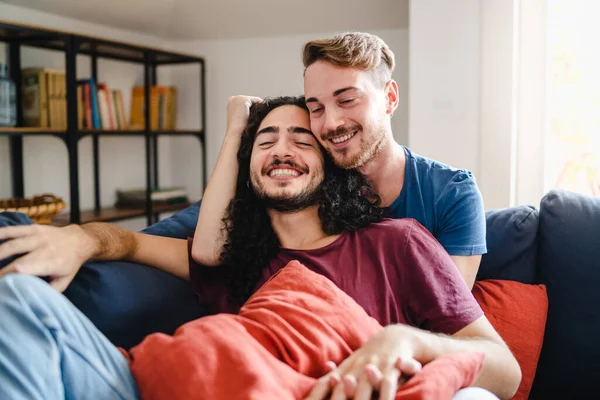浪漫的男同性恋伴侣温柔地拥抱在客厅沙发上 同性恋伴侣亲密地爱抚坐在沙发上 男女同性恋 双性恋 变性者和两性人生活方式的概念 — 图库照片